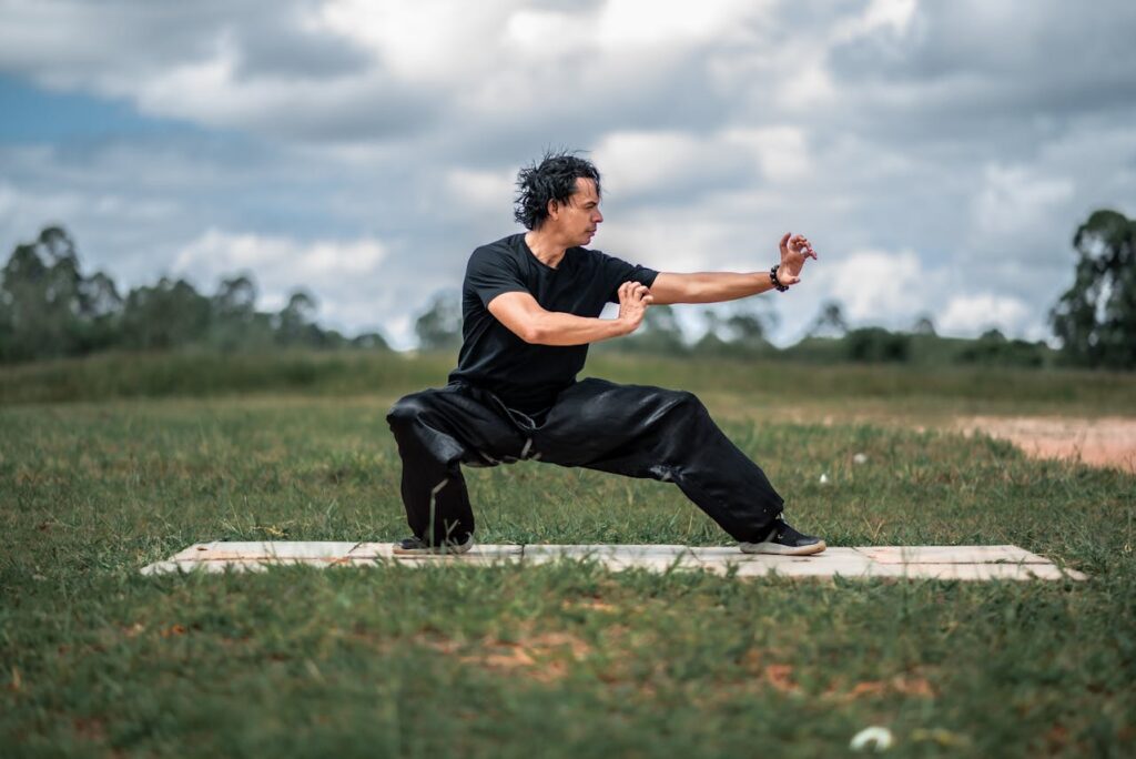 A person practicing tai chi in a field