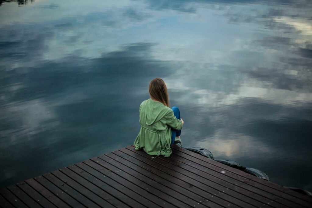 Image of a woman sitting on a dock looking out over water